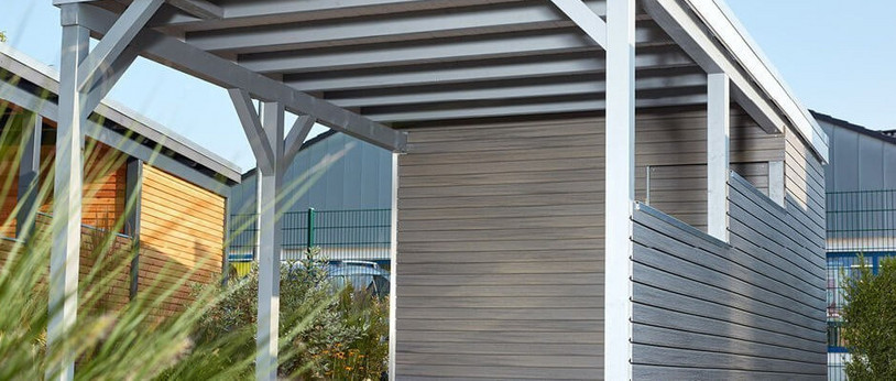Carport mit Holzdach als Unterstand für ein geparktes Auto.
