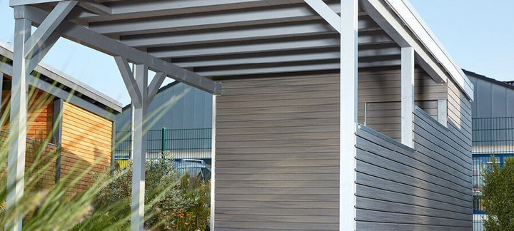 Carport mit Holzdach als Unterstand für ein geparktes Auto.