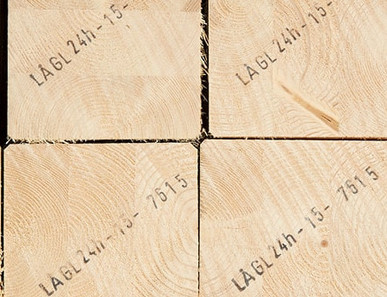 Gestapelte Brettschichtholzbalken mit sichtbarer Jahresringstruktur und Markierungen für den Holzbau.
