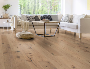Im Wohnzimmer wurde Parkett in Langdielen-Optik verlegt. Ein Sofa und einige liebevoll platzierte Dekoelemente runden das gemütliche Ambiente ab.