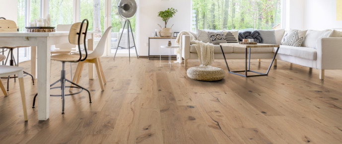 Im Wohnzimmer wurde Parkett in Langdielen-Optik verlegt. Ein Sofa und einige liebevoll platzierte Dekoelemente runden das gemütliche Ambiente ab.