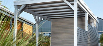 Carport mit Holzdach als Unterstand für ein geparktes Auto.