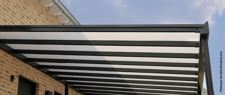 Moderne Überdachung mit transparenter Dacheindeckung aus Kunststoffplatten und stabiler Metallkonstruktion.