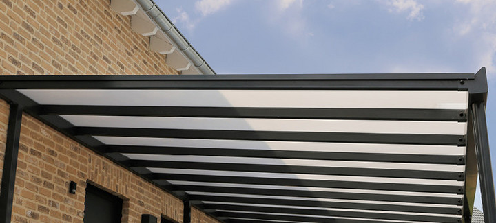Moderne Überdachung mit transparenter Dacheindeckung aus Kunststoffplatten und stabiler Metallkonstruktion.