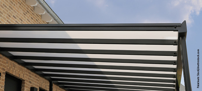 Moderne Überdachung mit transparenter Dacheindeckung aus Kunststoffplatten und stabiler Metallkonstruktion.