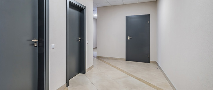Mehrere anthrazitfarbene Wohnungstüren, Blick vom Treppenhaus.