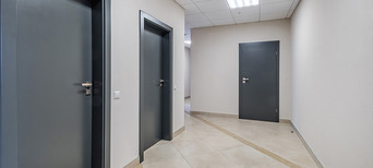 Mehrere anthrazitfarbene Wohnungstüren, Blick vom Treppenhaus.