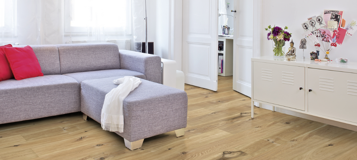 Im Wohnzimmer ist Parkett in Langdielen-Optik verlegt. Dazu passt ein Ecksofa mit bunten Kissen.